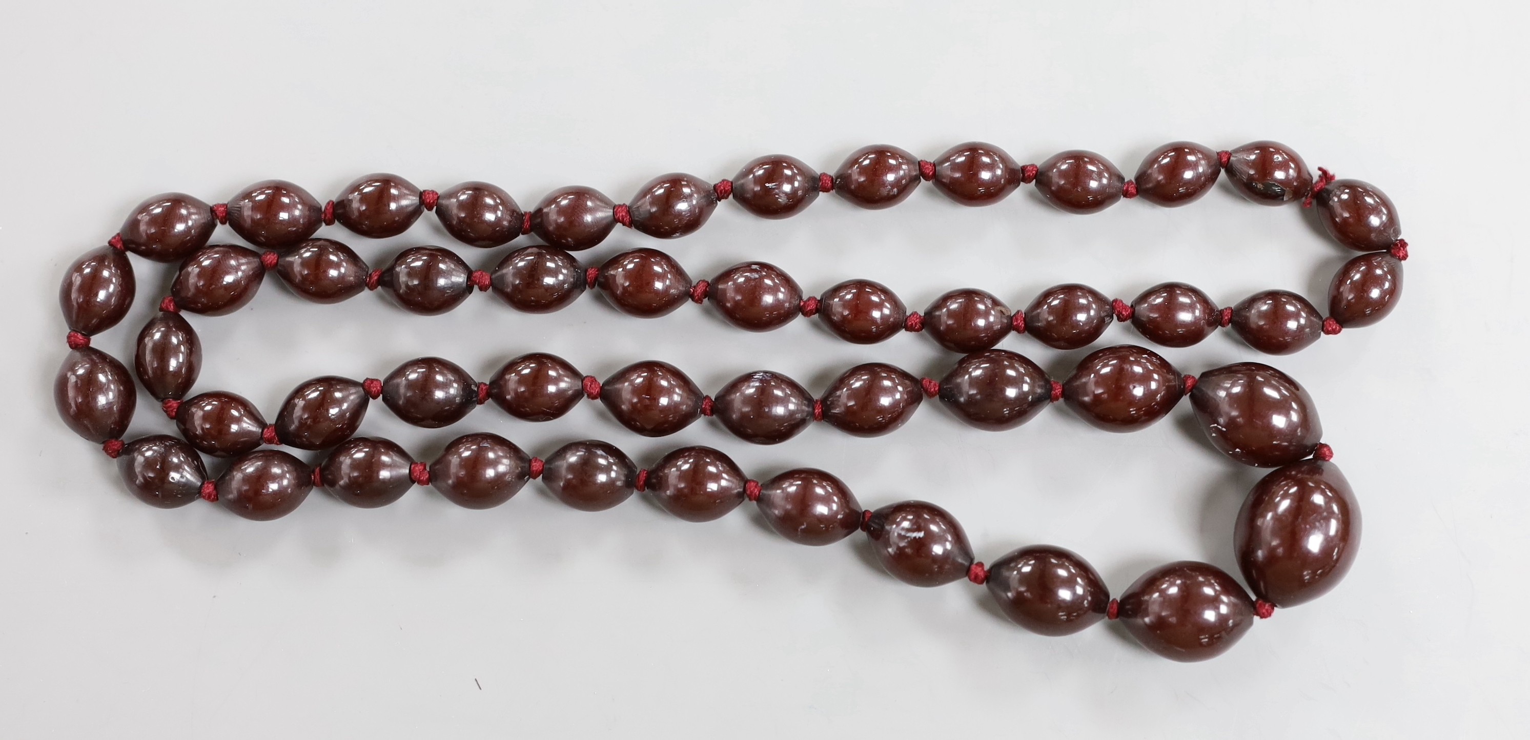 A single strand graduated oval simulated cherry amber bead necklace, 94cm, gross weight 100 grams.